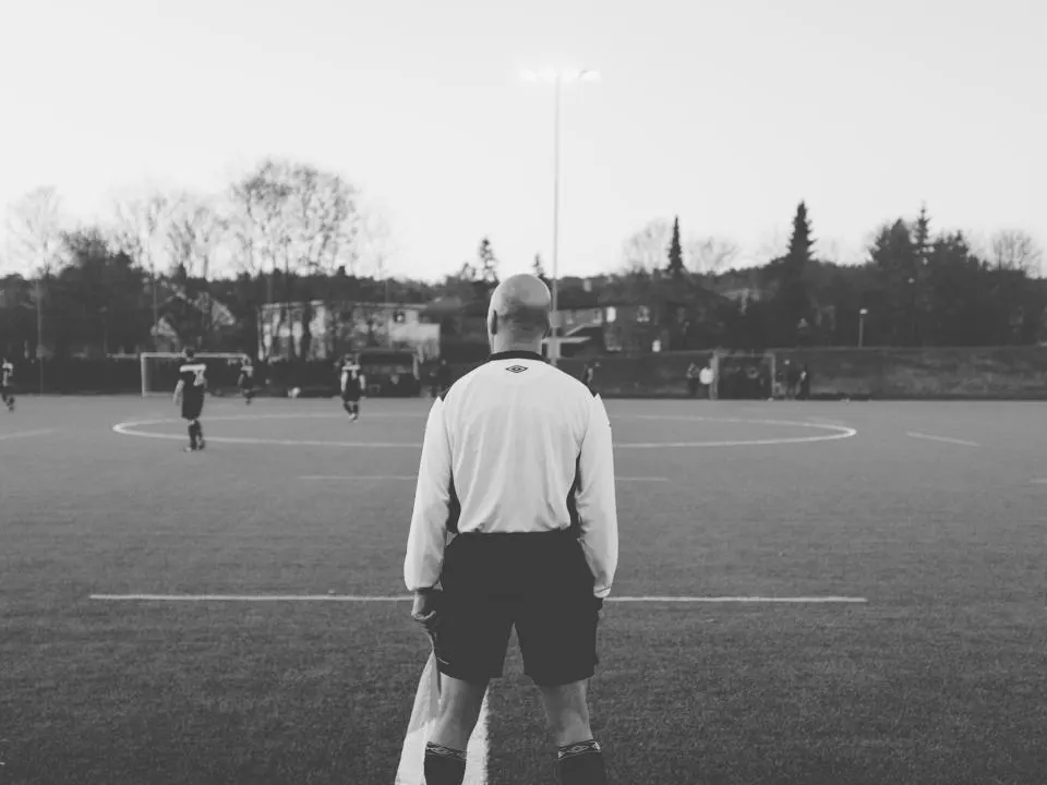 Referee holding a football on a pitch